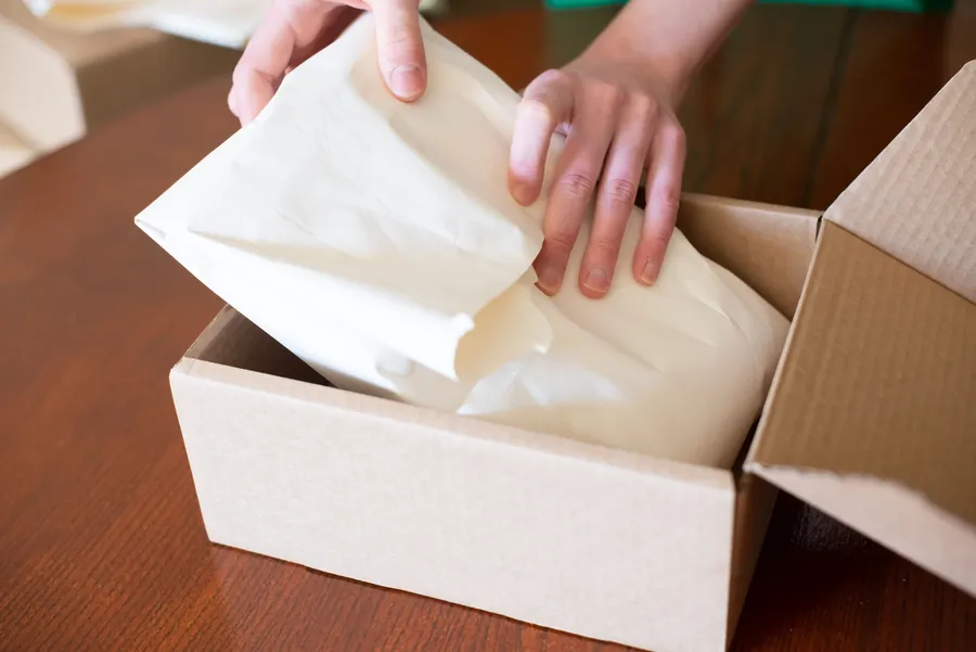 Hands packing a customer order in a cardboard box